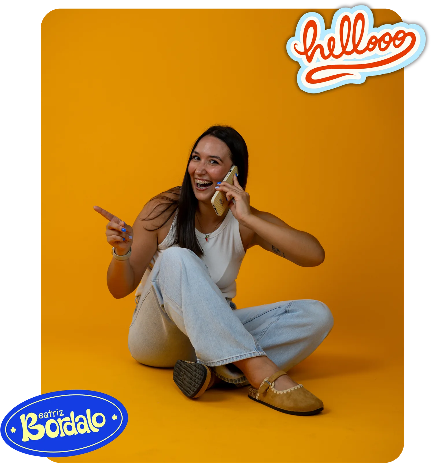 Beatriz Bordalo sentada no chão, sorridente, ao telefone e a apontar